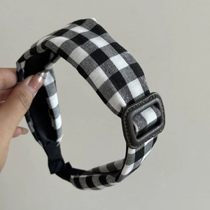 Vintage black and white gingham headband with decorative brown buckle on a light background