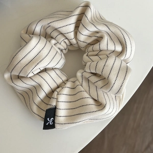 Striped beige fabric scrunchie with black dotted pattern and woven label for ponytail