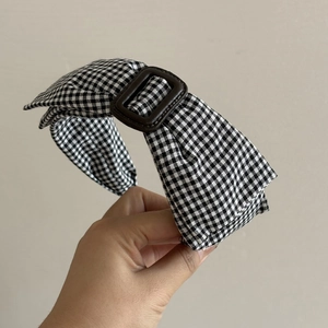 Detailed view of a vintage gingham headband with a brown decorative buckle accent