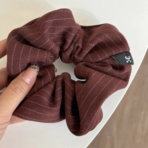 Detail view of burgundy striped scrunchie with white dots and woven brand label