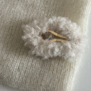 Gros plan sur une pince à cheveux en peluche grise sur tricot blanc pour style hivernal