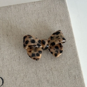 Detail of French leopard print bow hair clip with handmade gold lettering on fabric