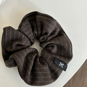 Detail of coffee brown striped scrunchie with soft fabric texture and a small woven label