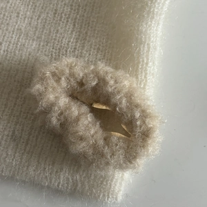 Détail macro d'une pince à cheveux nuage en peluche blanche avec texture tricotée et bouton