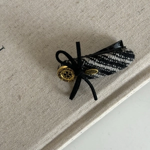 Detail of tweed bow hair clip with vintage gold button and Love metal charm