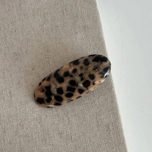 Detail of oval leopard print acetate hair clip featuring gold France Handmade logo