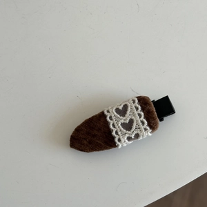 Detail von süßer Retro-Haarklammer aus braunem Cord mit weißer Herzspitze auf Metallclip