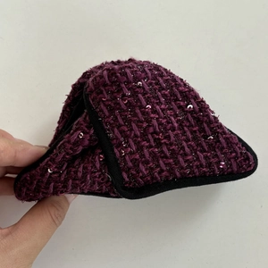 Detailed view of dark purple tweed hair accessory with sequins and black fabric trim