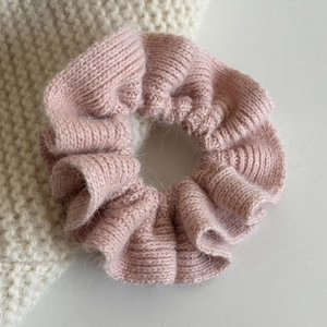 Nahaufnahme eines weichen rosa Mohair-Strick-Scrunchies mit flauschiger Textur und Falten