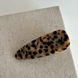 Detail of tortoise shell hair clip with France Handmade logo on beige linen fabric
