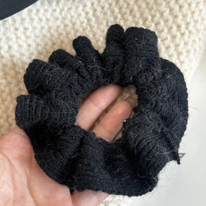 Detailansicht eines schwarzen Strick-Scrunchies mit Mohair-Textur und Häkelmuster