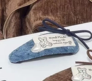 Nahaufnahme der Haarklammer aus blauem Denim mit Herzperle und kleinem Schleifendetail