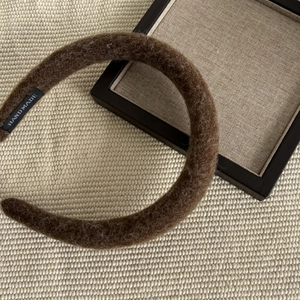 Retro thick wool headband in dark brown with handcrafted woven label on beige mat