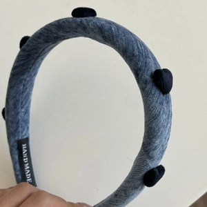 Detailansicht eines dunkelblauen Samt-Stirnbands mit handgefertigtem Etikett und Textur