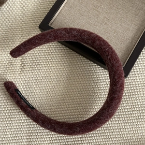Macro detail of thick burgundy wool headband with a black handmade textile label