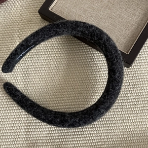 Detail of a handmade black wool plush headband showing thick sponge filling and soft texture