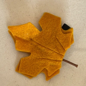 Detail of handmade maple leaf hair clip crafted from thick ginger yellow felt material