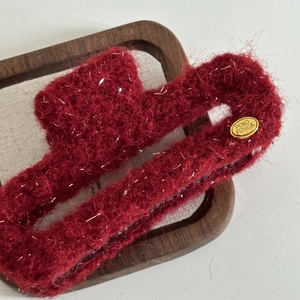 Macro shot of red plush shark hair claw clip with silver sparkles and gold metal logo