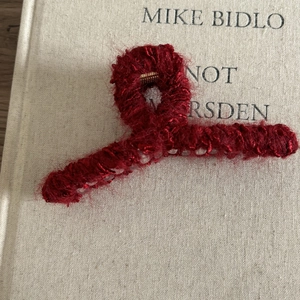 Détail d'une pince à cheveux en peluche rouge sur un livre d'art pour le style automne-hiver