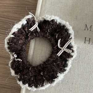 Gros plan d'un chouchou en tricot marron avec bords en dentelle beige sur un livre