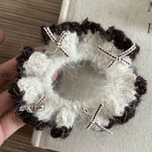 Détail macro du chouchou tricoté bicolore en laine pelucheuse blanche et marron foncé