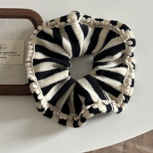 Knitted black and white striped hair scrunchie with cream pom-pom trim for autumn and winter