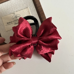 Detail view of the large wine red satin bow hair claw clip with glossy black teeth
