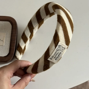 Gestricktes Stirnband in Braun und Weiß mit Bärenetikett im gemütlichen Winterstil