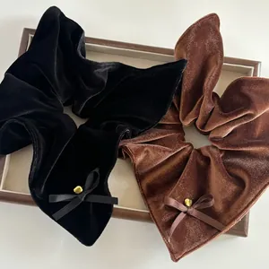 Detail von Samt-Haargummis in Schwarz und Kaffeebraun mit goldenen Herz-Anhängern
