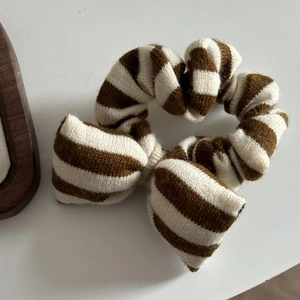 Nahaufnahme eines braun gestreiften Strick-Scrunchies mit einer süßen Schleife