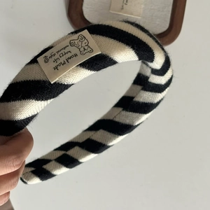 Detailed knit texture of a black and white striped headband with a cute bear label