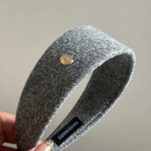 Gray textured wool headband with golden metal detail and handmade label, stylish wide hairband
