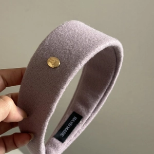 Detail view of handmade purple wool headband featuring a gold metal buckle and soft texture