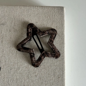 Dettaglio di fermaglio a stella con stampa leopardata su sfondo di lino