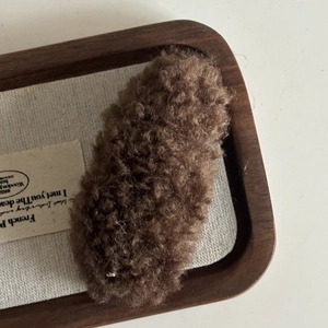 Detail of coffee brown teddy fleece hair clip with fluffy lamb wool texture on tray