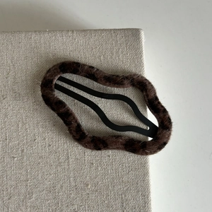 Dettaglio di un fermaglio per capelli leopardato con texture soffice e clip BB in metallo
