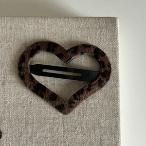 Dettaglio del fermaglio per capelli a forma di cuore con stampa leopardata e metallo