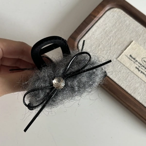 Vue détaillée de la pince à cheveux en peluche grise avec nœud noir et cristal brillant