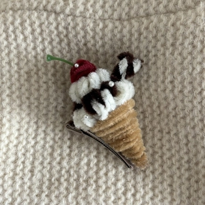 Handmade plush ice cream hair clip with cherry and pearls on warm knitted background