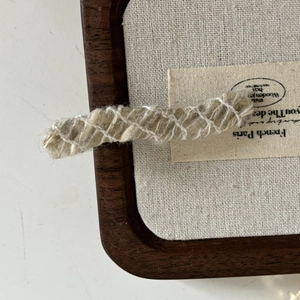 Detailed view of French vintage khaki wool knitted hairpin with white thread accents