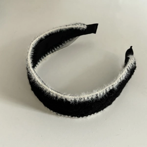 Close-up of black knitted headband with white faux fur trim and soft inner lining