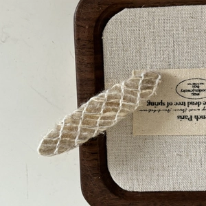 Detailed close-up of a French wool blend hair clip with white mesh texture on linen