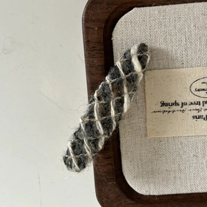 Close-up of wool hair clip featuring grey white woven yarn and fine mesh texture details