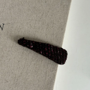 Elegant tweed triangular hair clip in plum and black weave on textured background