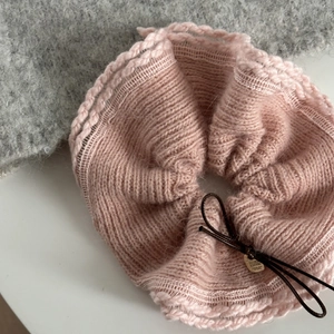 Chouchou en maille rose avec nœud en laine et breloque dorée en vue à plat chaleureuse