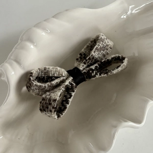 Detailed view of vintage brown and beige checkered bow hair clip on an elegant tray