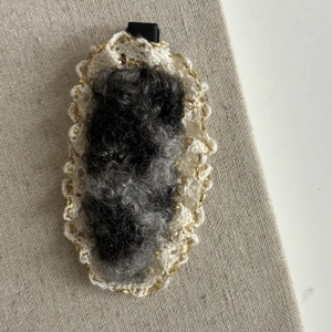 Dettaglio macro del fermaglio per capelli in peluche grigio con pizzo bianco all'uncinetto