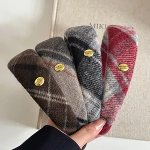 Detail of plaid wool headband with gold metal label showing text Believe in Yourself