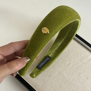 Detail of green velvet wide headband with golden metal tag and handmade label