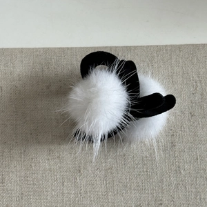 Détail de pompons en fausse fourrure blanche sur un élastique en velours noir élégant